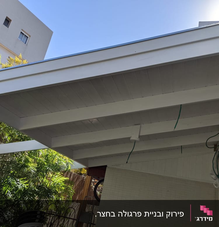 גג עץ לבן עם קורות חשופות וחוטים ירוקים תלויים